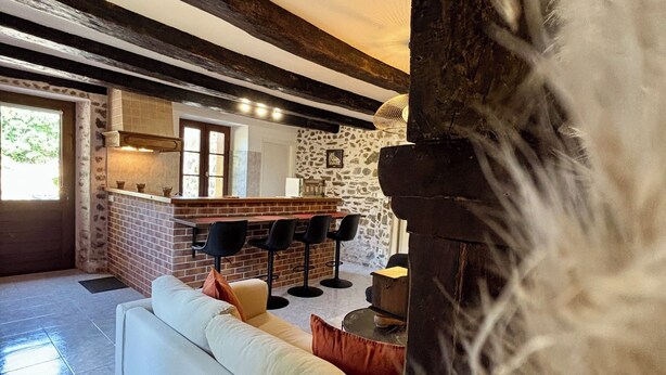 A cozy living area with a sofa, a fireplace, and a kitchen in the background.