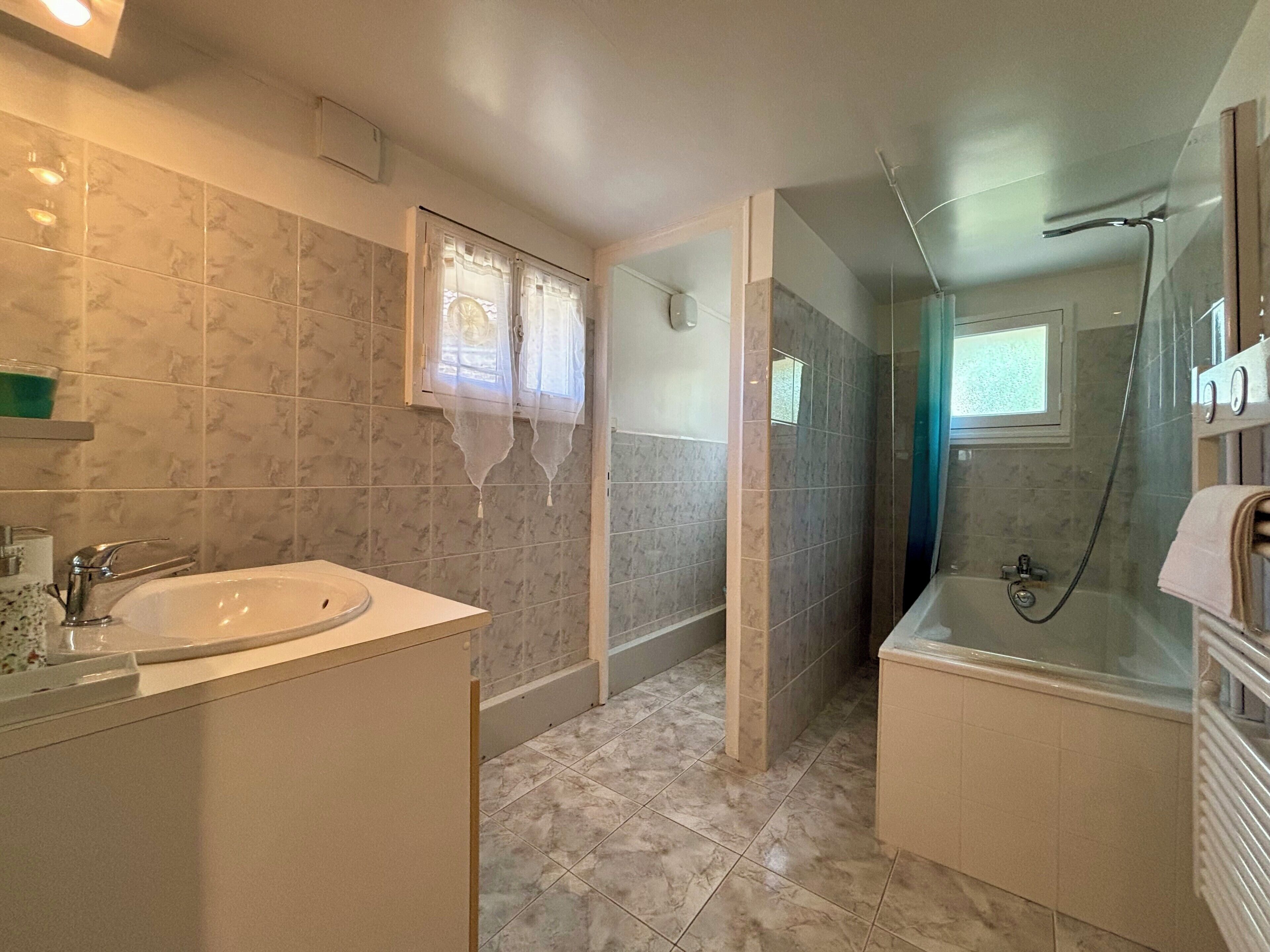 A bathroom with a sink, mirror, shower, and toilet.