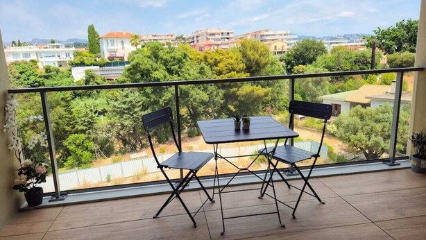 Un balcón con mesa y sillas, con vistas a una zona residencial con casas y árboles.