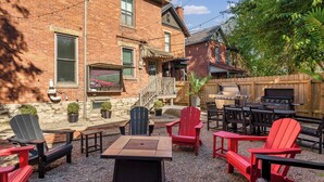 Un jardin avec un espace aménagé pour se détendre en plein air, un barbecue et une cheminée en pierre.