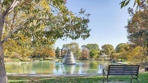 Un parc avec une fontaine, un banc et des arbres.