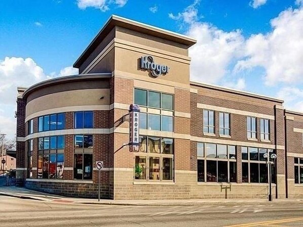Un magasin Kroger avec une entrée d’angle, de grandes fenêtres et une façade en briques.