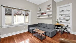 Un salon comprenant un canapé d’angle gris, une petite table basse, une table à manger avec des chaises et des étagères intégrées ornées d’objets décoratifs.