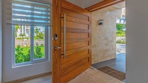 A wooden door with a modern handle, a glass door with horizontal blinds, and a stone wall with a light fixture. - Palm Villa 4BR Luxe pool retreat (Sosúa)