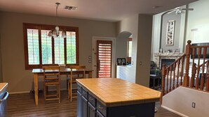 A kitchen with wooden cabinets, a tiled island, and a dining area with chairs and a table. - Relax in the Gilbert Getaway (Gilbert)
