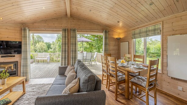 Een gezellig interieur van een vakantiehuisje, met een bank, eettafel en stoelen.