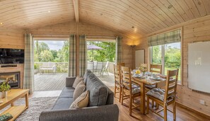 Un intérieur de chalet chaleureux avec un canapé, une table à manger et des chaises.