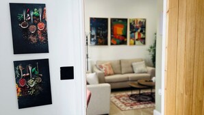 A doorway leading to a living room with a sofa and a coffee table. There are three artworks on the wall.