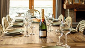 Une table à manger dressée pour six personnes, avec des verres à vin, des assiettes et une bouteille de vin.