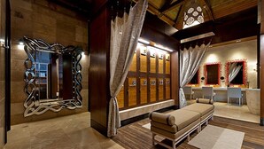 Una habitación con un banco de madera, un espejo de marco original y varios casilleros al fondo.