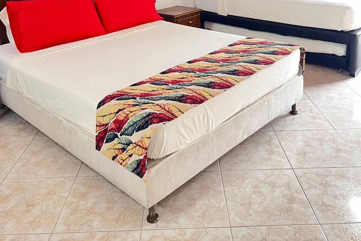 A bedroom with a large bed, a smaller bed, a nightstand, a wall-mounted shelf, and a painting.