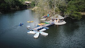 Eine Flussanlegestelle mit Kanus, eine kleine Insel mit Laube und eine Brücke im Hintergrund.