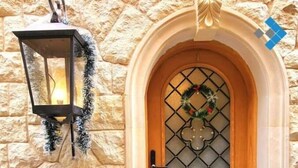 A stone wall with a wooden door featuring a decorative glass panel and a wreath. - 2BRs with garden- Three Sisters Villa 3 (New Cairo City)