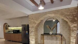 A spacious living area with a stone archway, a round rug, and a modern kitchen in the background. - 2BRs with garden- Three Sisters Villa 3 (New Cairo City)