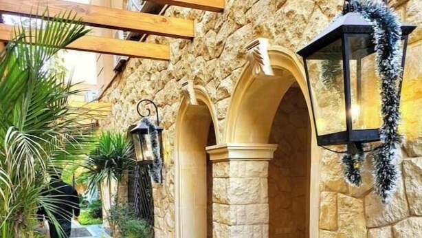 A stone-walled corridor with arches, potted plants, and a tiled floor. - 2BRs with garden- Three Sisters Villa 3 (New Cairo City)