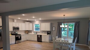 Una cocina moderna con armarios blancos, electrodomésticos de acero inoxidable y una zona de comedor con mesa y sillas.