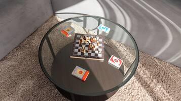 Een ronde glazen tafel met een schaakbord, twee boeken en twee speelstukken.