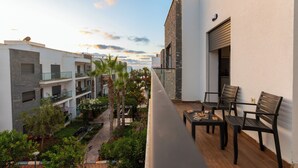 A balcony with a wooden floor, two black chairs, and a small table with a plate and a cup. - Garden Bay Signature AppartHotel (Sidi Rahal)
