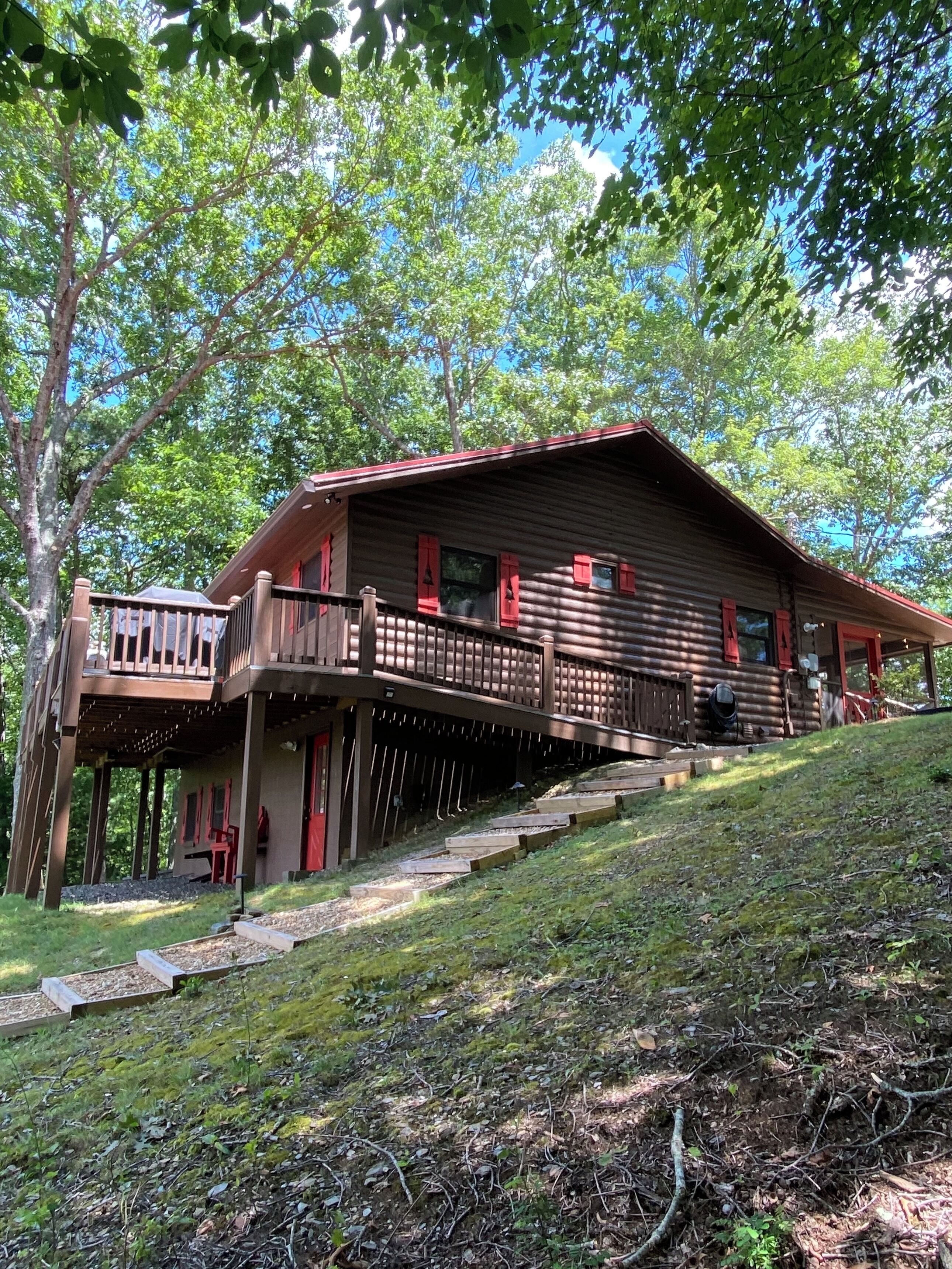 A cabin with a wooden exterior, a balcony, and a staircase leading up to the entrance.