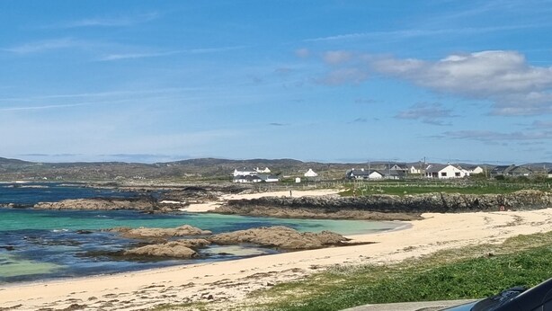 A coastal landscape with a sandy beach, rocky outcrops, and a row of white houses along the shore. - Lakeside House in picturesque Oughterard at the gateway to Connemara (Galway)