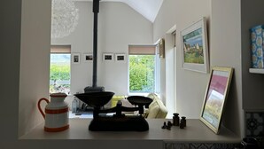 A cozy living room with a large window, a black stove, and a decorative hanging light fixture. - Lakeside House in picturesque Oughterard at the gateway to Connemara (Galway)