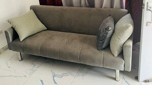 A sofa with two pillows, a patterned curtain, and a tiled floor. - Small apartment-style villa near the beach (Puerto Plata)