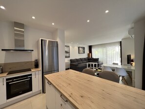 A modern kitchen with a stainless steel refrigerator, a wooden countertop, and a built-in oven.