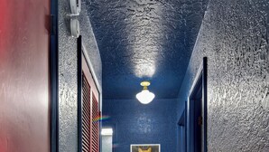 A hallway with a red door, a blue wall, and a wooden floor. - We're All Mad Here! - A Wonderland Escape in Tulsa (Tulsa)