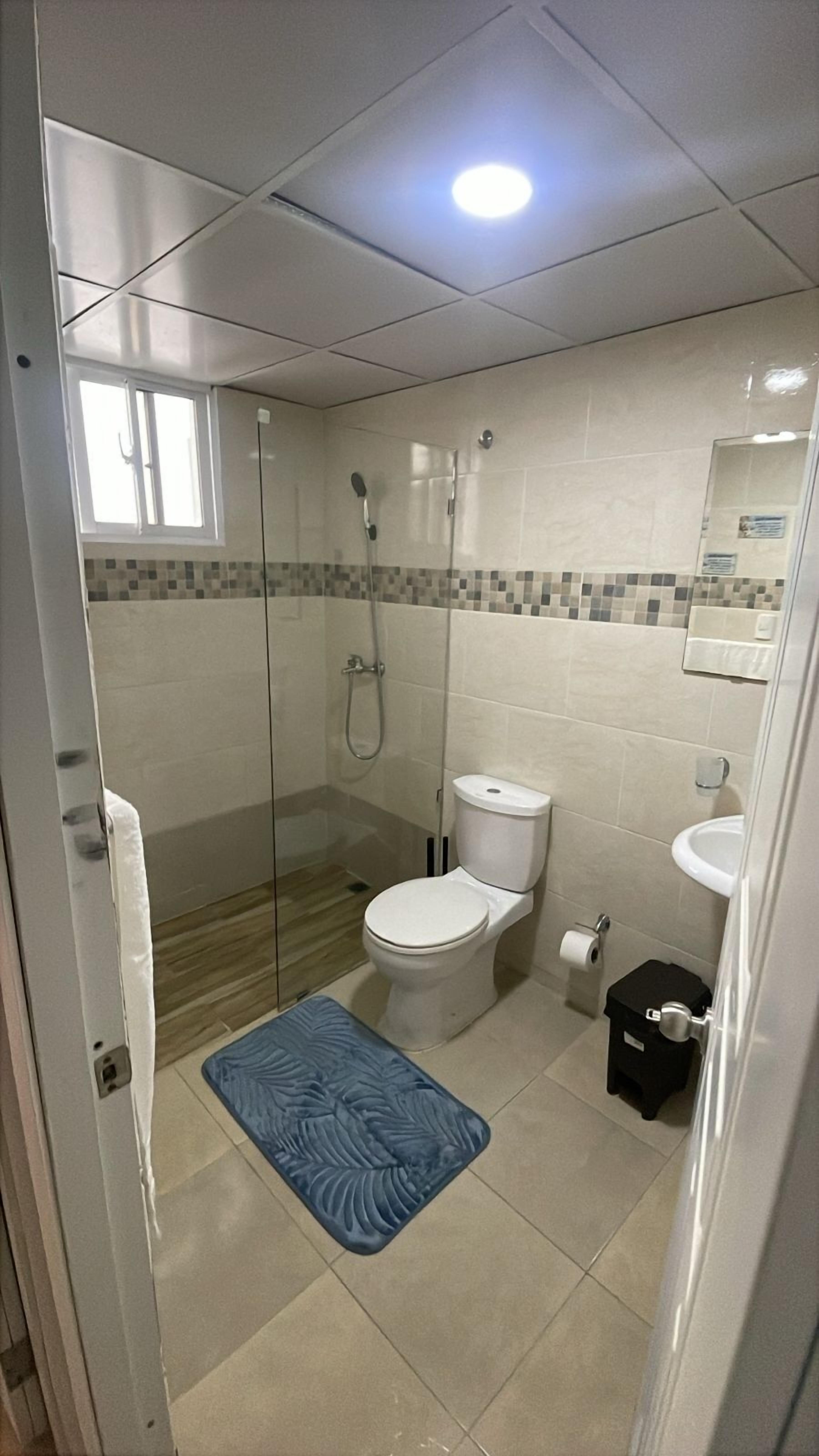 Une salle de bain avec une douche à parois de verre, des toilettes et un lavabo.