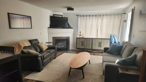 Ein modernes Wohnzimmer mit Kamin, zwei Sofas, einem Couchtisch und einem Schrank.