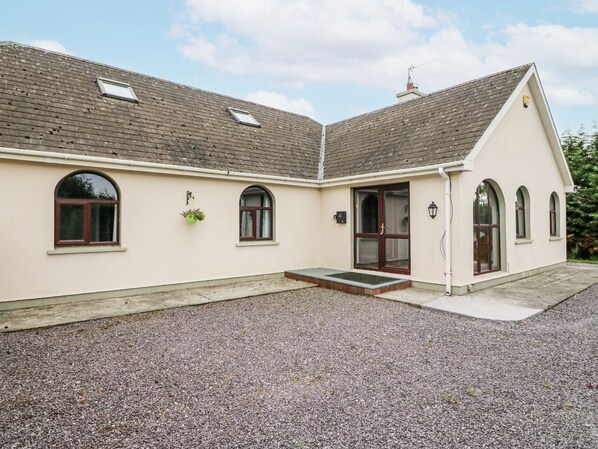 A two-story building with a gravel driveway, a front entrance with a door and steps, and multiple windows. - LILLY'S BUNGALOW, pet friendly in Clonakilty, County Cork (Timoleague)