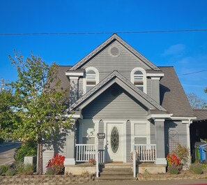 A two-story house with a gabled roof, a front porch with white railings, and a mailbox with a decorative plate. - Pippa's Place Sebastopol - Walking Distance to Barlow! (Sebastopol)