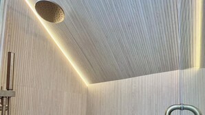 Ein moderner Duschbereich mit Holzwand, integriertem Sitzplatz und Handbrause.