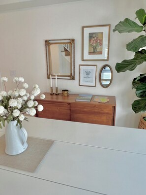 A reception desk with a white vase of flowers, a mirror, framed pictures, and a potted plant. - Pippa's Place Sebastopol - Walking Distance to Barlow! (Sebastopol)