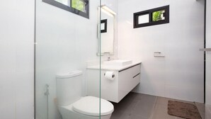 Un baño moderno con inodoro, lavamanos y cabina de ducha de vidrio.