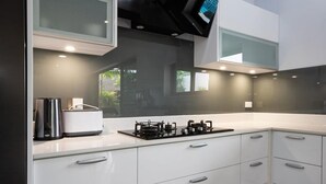 Una cocina moderna con armarios blancos, una estufa a gas integrada y una cafetera.