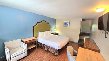 A hotel room with a bed, two bedside tables, a chair, a desk, and a television.