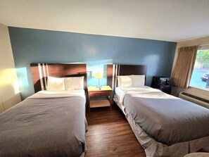 A hotel room with two beds, a nightstand, a lamp, and a window with a view of the outside. - Brentwood Inn Richmond South (Richmond)