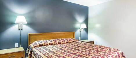 Quarto com cama de madeira, duas mesas de cabeceira e duas luminárias na parede.