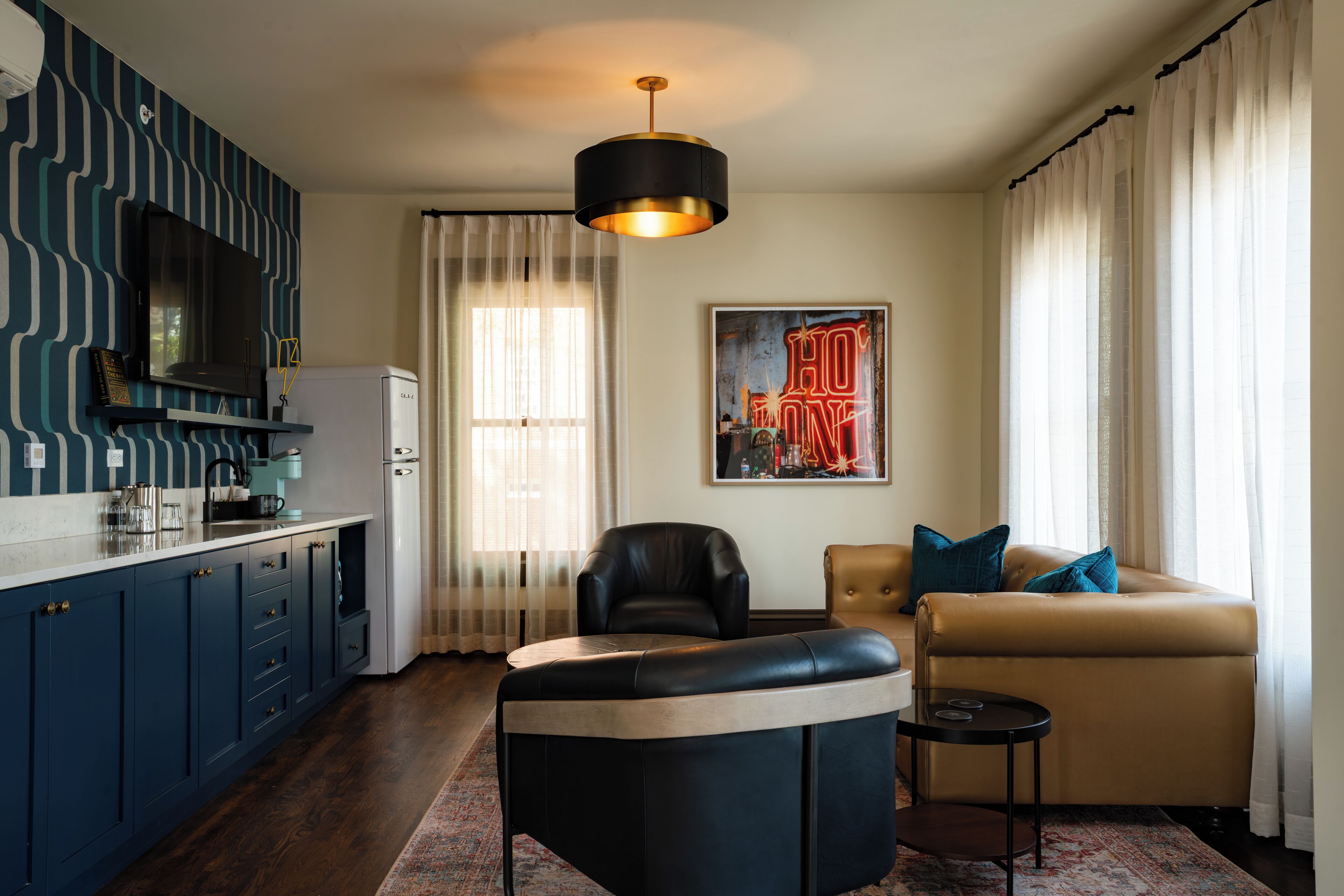 A modern living room with a sofa, a black leather chair, a small side table, and a large painting.