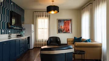 A modern living room with a sofa, a black leather chair, a small side table, and a large painting.
