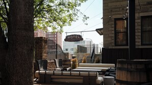 A hotel patio with outdoor seating, a sign indicating the hotel name, and a view of the cityscape in the background. - Hotel Pontotoc  (Memphis)