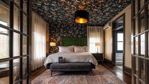 A bedroom with a large bed, a green headboard, and a patterned rug. - Hotel Pontotoc  (Memphis)