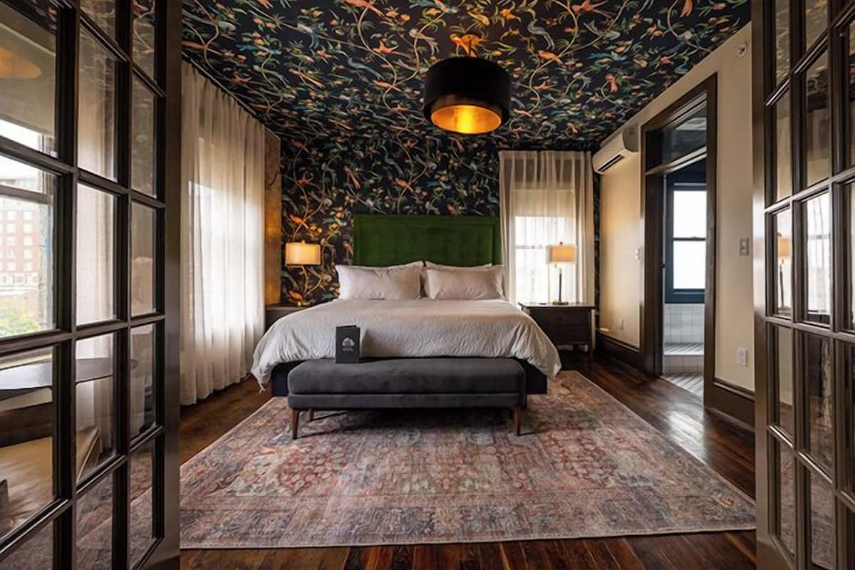Un dormitorio con una cama grande, un cabecero verde y una alfombra estampada.