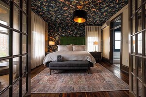 A bedroom with a large bed, a green headboard, and a patterned rug.