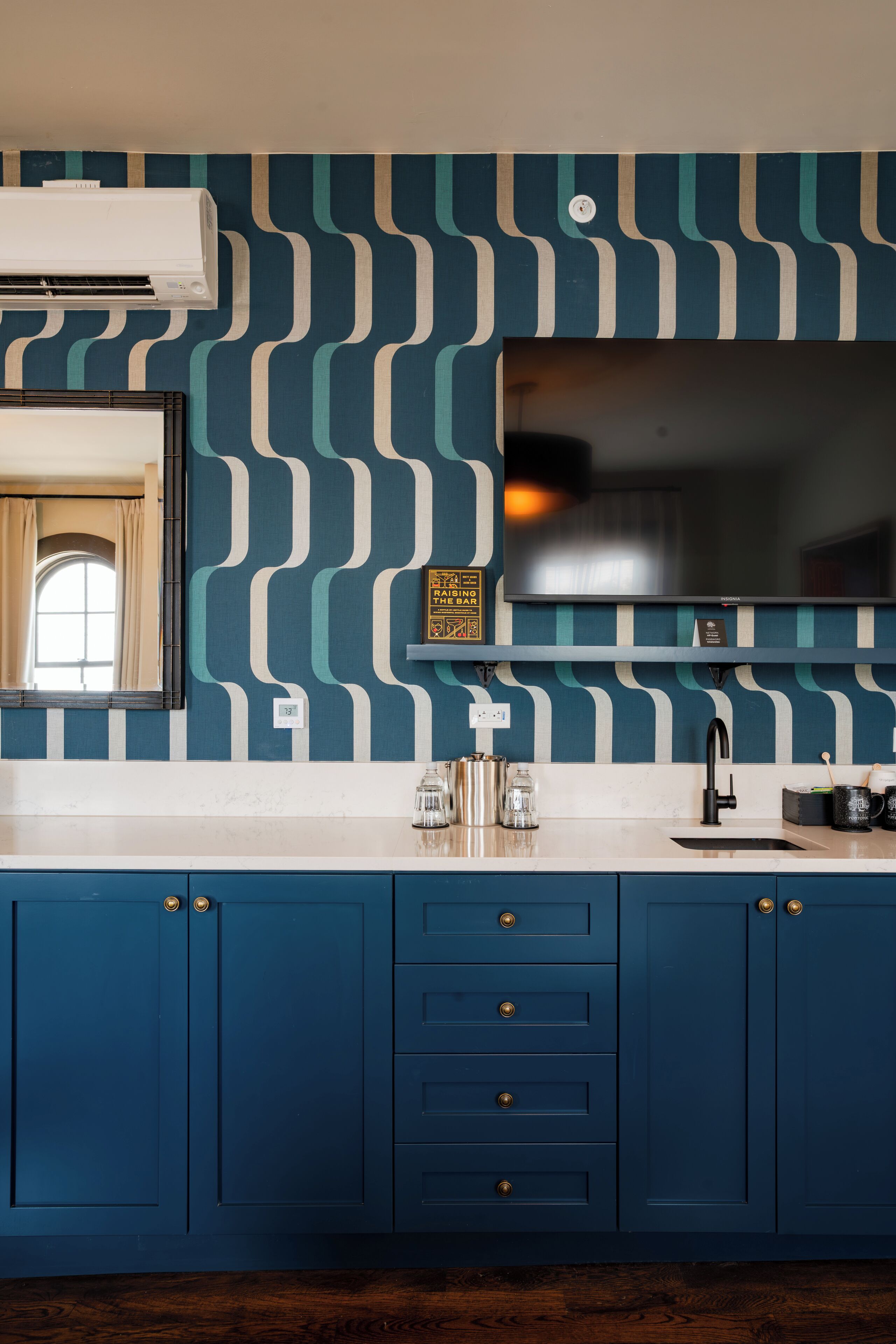 A kitchen with blue cabinets, a white countertop, and a patterned backsplash.