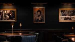 A dimly lit restaurant with dark walls, framed artwork, and leather seating. - Hotel Pontotoc  (Memphis)