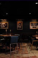 A dimly lit restaurant with dark walls, framed artwork, and leather seating.