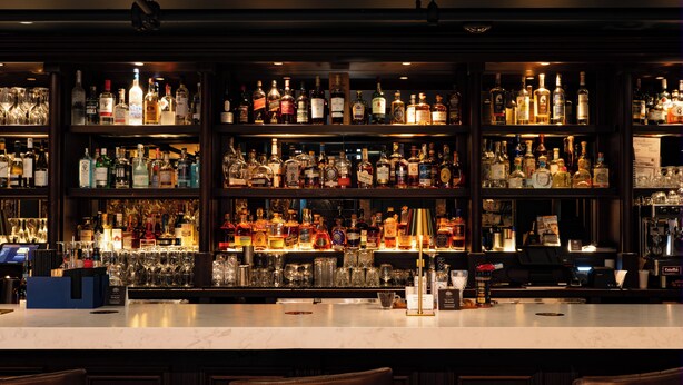 A bar area with shelves stocked with various liquor bottles and glasses. - Hotel Pontotoc  (Memphis)