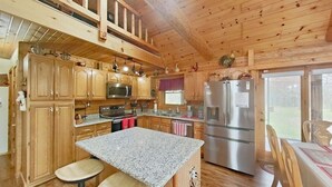 Une cabane en bois dotée d’une cuisine avec des comptoirs en granit, des appareils en acier inoxydable et des armoires en bois.